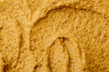 Mustard sauce with grains close-up. Hot spices as a background. Texture of Dijon mustard.