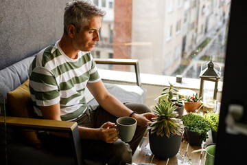 Photo of a man replanting plants on the balcony of loft apartment