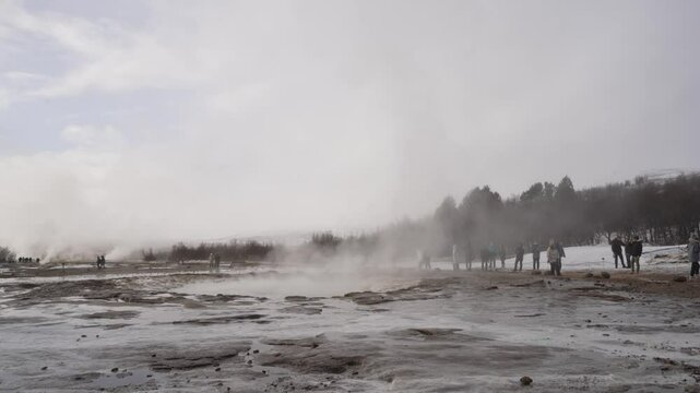 View of people around the erupting Strokkur geyser at Geysir Hot Springs in winter, Golden Circle, Western Region, Iceland