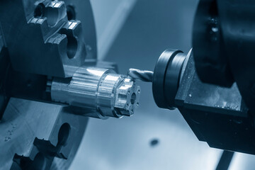 The CNC lathe machine milling cut the metal shaft parts in the light blue scene.