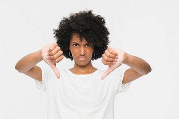 Headshot of young black woman showing fingers thumbs down as refusal sign. Studio portrait of unhappy dissatisfied girl lady expressing dislike isolated on white background. People emotions concept © InsideCreativeHouse