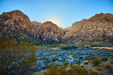 Obraz premium Rugged Red Rock Mountains at Sunrise with Desert Vegetation in Foreground