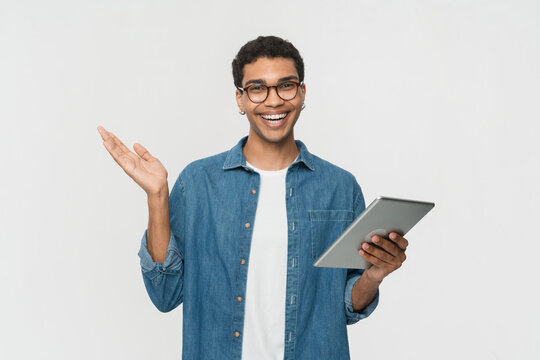 Young happy cool African American teenager student boy wearing casual holding pad using digital tablet computer technology browsing, elearning standing isolated on light white background.