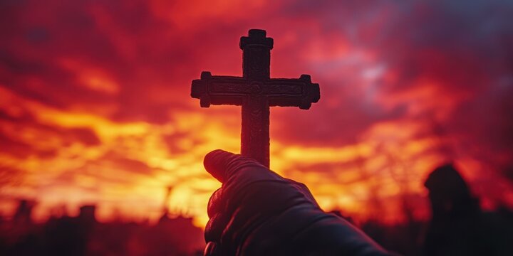 Silhouette of a person holding a cross against a fiery sunset backdrop in a serene landscape - Powered by Adobe