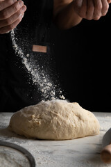 Fototapeta premium Male hands making dough for pizza, bread, pasta. Cooking bread. Kneading the Dough. Isolated on dark background. Copy space, production of flour products