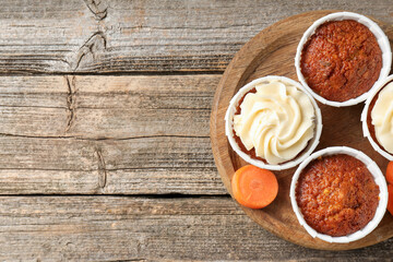 Tasty carrot muffins and fresh vegetable on wooden table, top view. Space for text