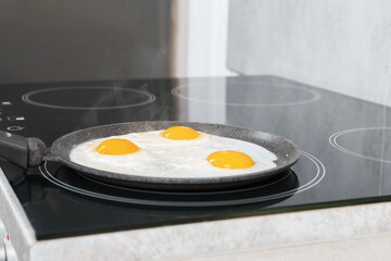 Cooking tasty eggs on frying pan in kitchen, closeup