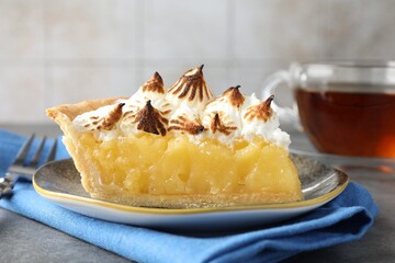 Piece of delicious pie with browned meringue on grey textured table, closeup