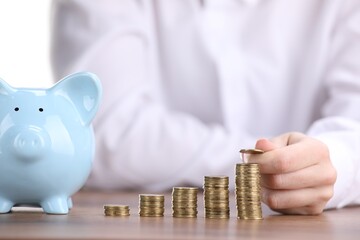 Man putting coins onto stacks of ones at wooden table, closeup
