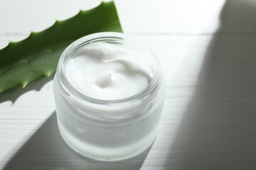 Cream and aloe leaves on white wooden background, closeup