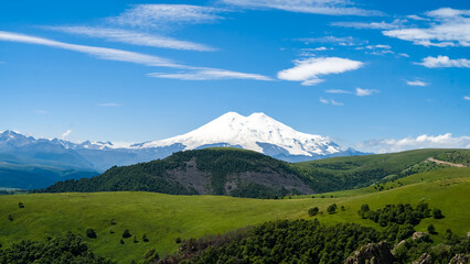 Fototapeta premium snowy mountain peaks on a background of green hills