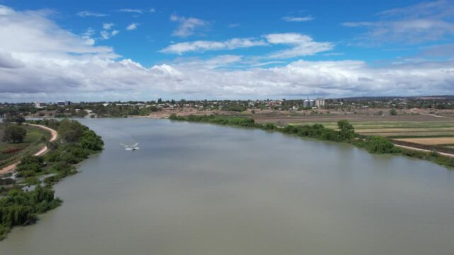 Aerial view of the serene Murray River with wakeboarder and picturesque town, Murray Bridge East, South Australia, Australia.