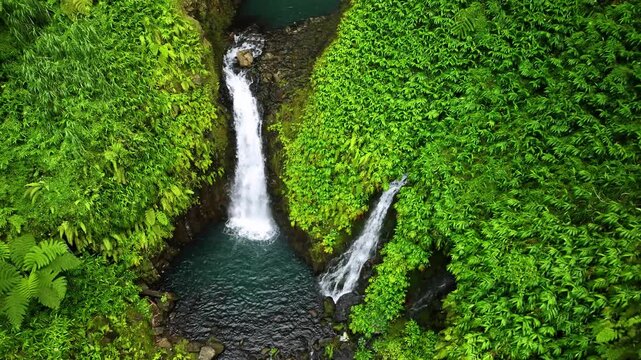 Aerial view of a breathtaking waterfall cascading through lush greenery in a tropical forest, Apia, Tuamasaga, Samoa.