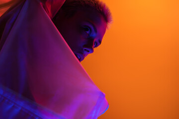 A futuristic art-inspired image of a woman illuminated by neon lights against a vivid orange backdrop.
