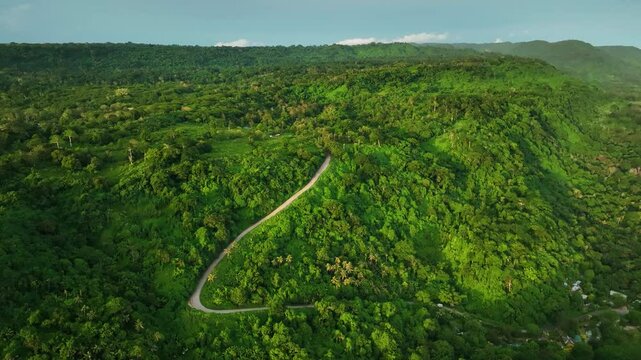 Aerial view of a breathtaking mountain and ocean landscape at sunset with a winding road surrounded by lush greenery, Port Vila, Shefa, Vanuatu.