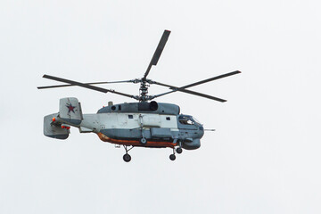 Flying helicopter against the blue sky. Air transport. The helicopter flies in the cloudy sky. Light color Rotorcraft.