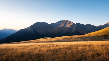 Breathtaking panoramic view of golden grasslands with majestic mountains under clear blue sky : Generative AI