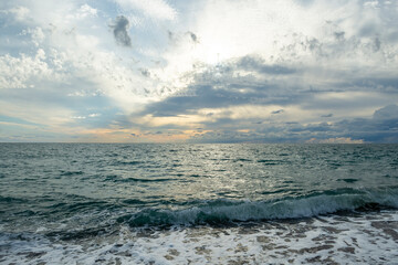 The sound of sea waves crashing on a pebble beach. The setting sun hid behind dark clouds.