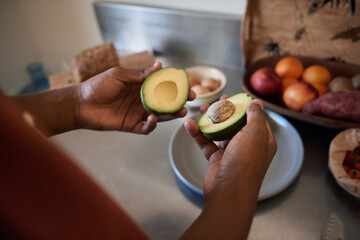African man cutting an avocado in half in his kitchen
