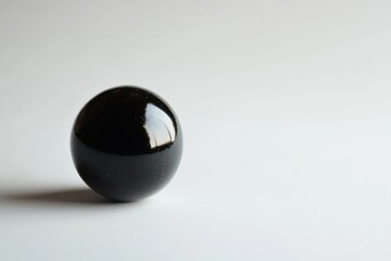 Smooth black obsidian sphere on simple light background with elegant reflections and shadows
