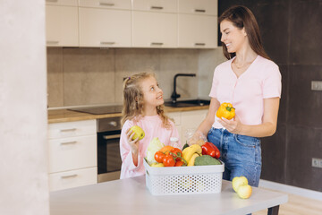 Mother and daughter unpacking fresh groceries in kitchen