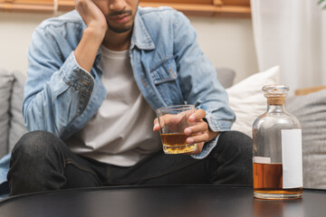 Health care alcoholism drunk, fatigue asian young man drinking beverage on table, alone depressed male drink booze on sofa at home. Treatment of alcohol addiction, suffer abuse problem alcoholism.
