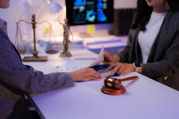 Two lawyers are examining legal documents and discussing contract details in a modern office, with...
