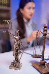 Lady Justice statue and scales are placed on a lawyer's desk, symbolizing the principles of law,...