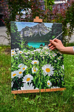 A colorful painting on an easel in a peaceful outdoor setting, with a brush nearby, capturing the process of creating art in nature.