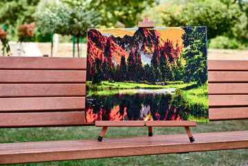 A vibrant painting displayed outdoors, placed on an easel amidst a beautiful natural landscape,...