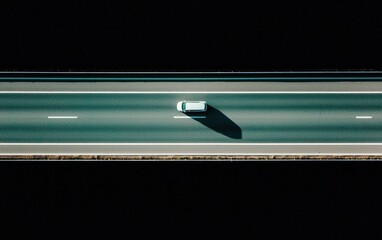 Aerial view of a white car driving on a dark highway against a starry night sky. The image has a pixelated, digital aesthetic