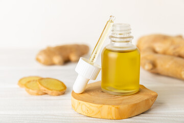 Ginger essential oil on texture background. Fresh ginger slices. Essence, serum, oil. Alternative...