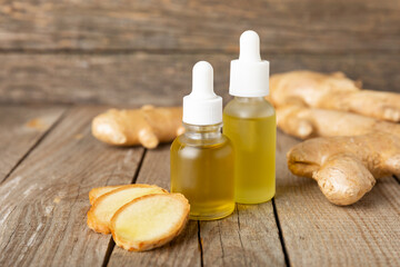 Ginger essential oil on texture background. Fresh ginger slices. Essence, serum, oil. Alternative...