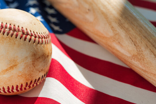 Close up of worn baseball and wooden bat on American Flag