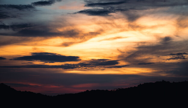 A mountain silhouette set against an orange and red sky at treasure mountain, tanay, philippines