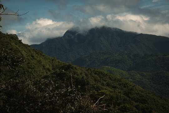 Dark Green Mountain Range with clouds overlapping the peak of the background mountain at treasure mountain, tanay, philippines
