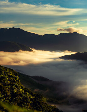 A mountain range surrounded by a sea of clouds during a warm sunset at treasure mountain, tanay, philippines