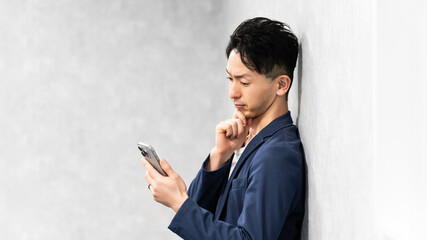 スマートフォンを見て考える男性ビジネスマン