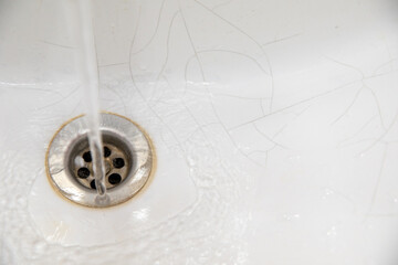 A white sink in the bathroom or toilet with cracks in the form of a spider web.