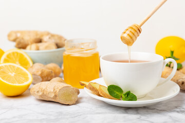 Cup of hot ginger tea with slices of ginger root on wooden background. Warming drink. Alternative...
