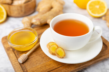Cup of hot ginger tea with slices of ginger root on wooden background. Warming drink. Alternative medicine. Tea with honey, lemon, ginger and mint. Space for text. Copy space
