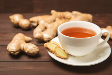 Cup of hot ginger tea with slices of ginger root on wooden background. Warming drink. Alternative medicine. Tea with honey, lemon, ginger and mint. Space for text. Copy space