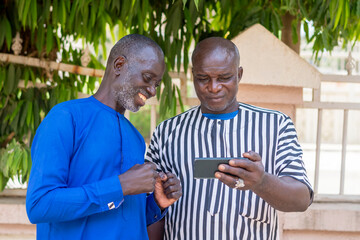two handsome african man feeling excited while operating cellphone