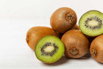 Kiwi on wooden background. Whole fruit and slices pieces of green kiwi on table. fresh ripe juicy kiwi. Tropical fruit. Organic fruit. Healthy eating. Space for text. Copy space.