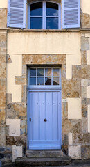 Old building facade featuring wooden door, iron balcony, and geometric stone wall pattern. For the background of your photos and collages