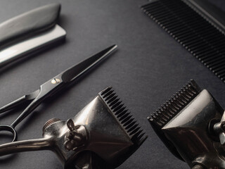 Antique barber tools are artfully placed on a dark surface, highlighting scissors, clippers, and a comb. This setup reflects the classic aspect of grooming and hairstyling