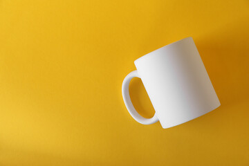 One blank white mug on yellow background, top view. Mockup for design