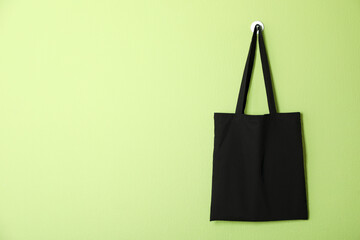 Black eco bag hanging on green wall. Mockup for design
