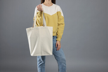 Woman with blank shopper bag on grey background, closeup. Mockup for design