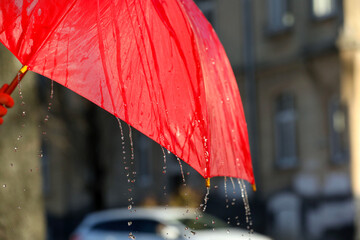 Open red umbrella under pouring rain outdoors, closeup